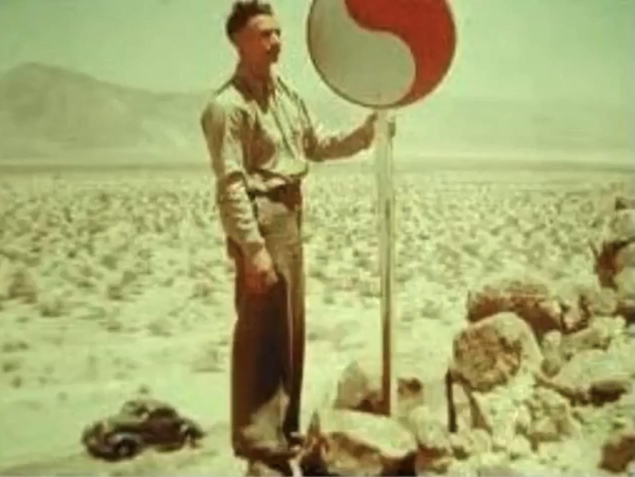 Unidentified historical scene showing a man holding a Monad standard in a desert-like landscape.